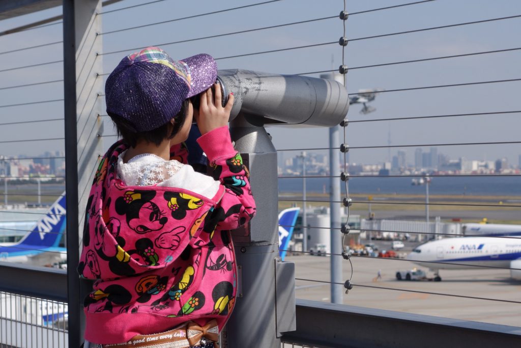 An AvGeek-in-training uses a telescope on HND T2's observation deck. See the cables?