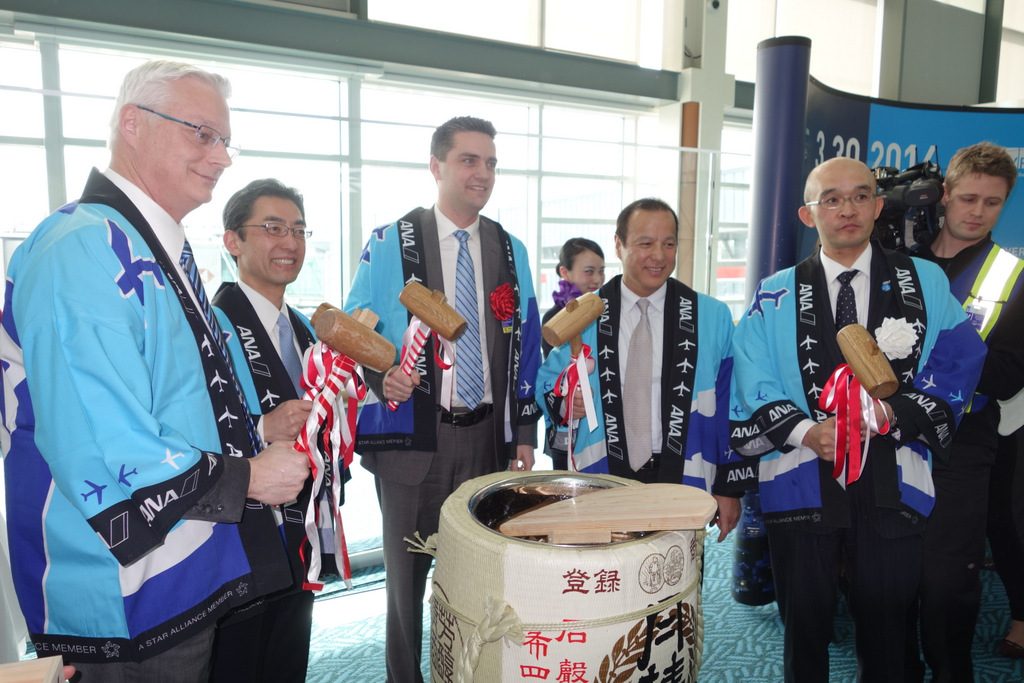 Inaugural flight dignitaries smash open the ceremonial barrel of sake
