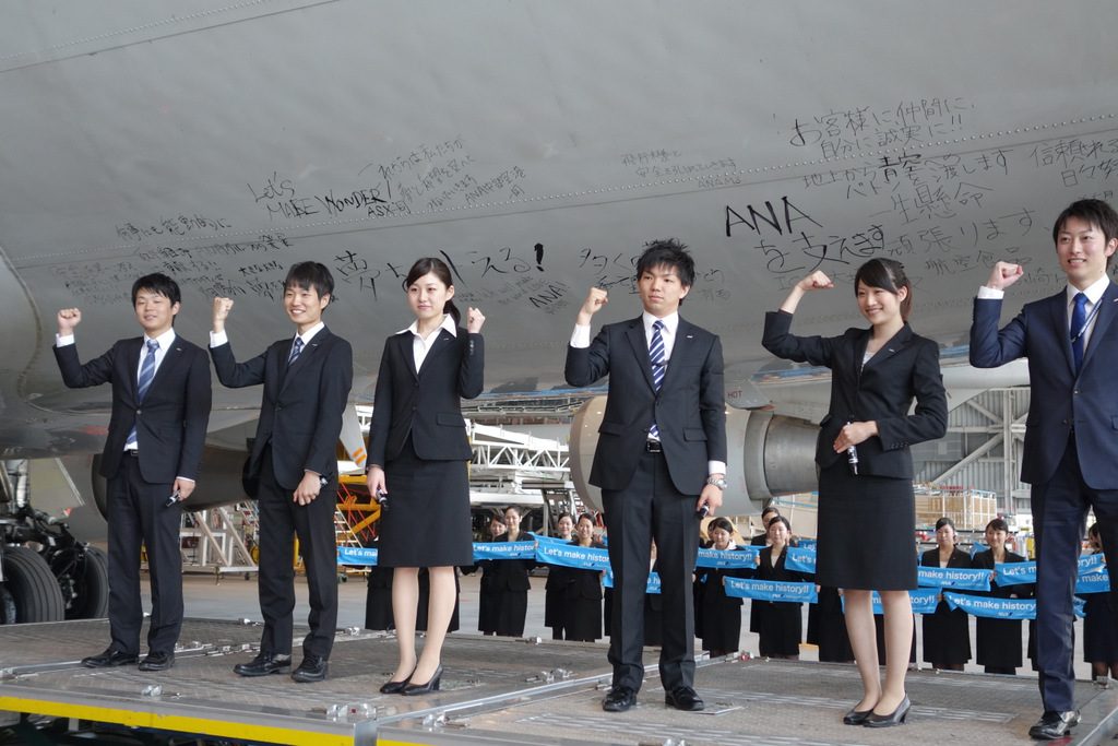 Enthusiastic new ANA employees sign the fuselage of ANA's last 747-400D after its final flight